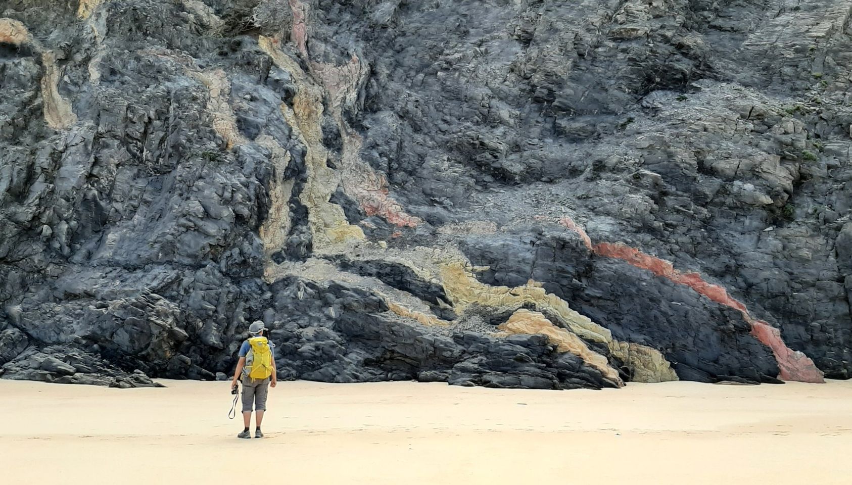 Eine Frau ist am Strand und schaut auf einen Berg.